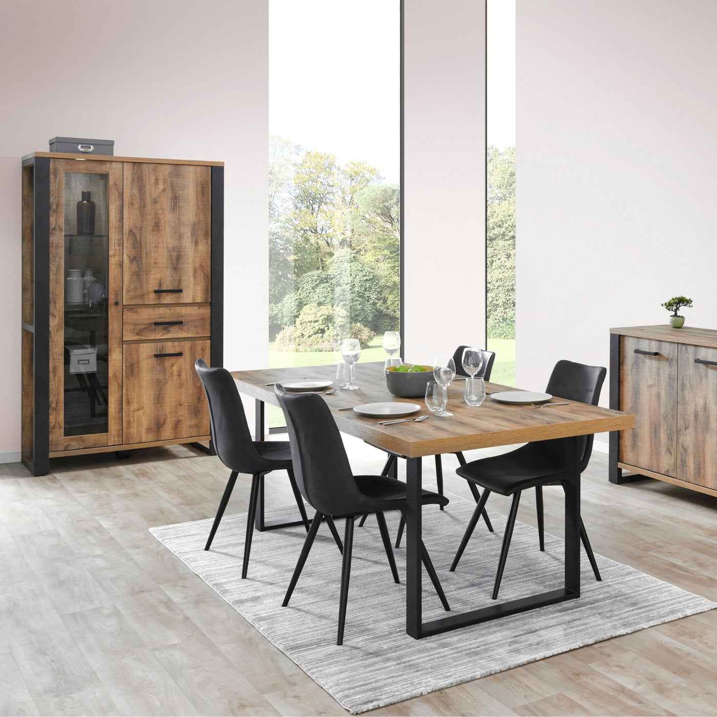 Salle à manger Onno (décor TROPIX), table dressée avec chaises noires entre la vitrine et le bahut, en ambiance lumineuse
